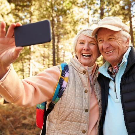 Vanhempi pariskunta patikoi metsässä selfietä ottamassa