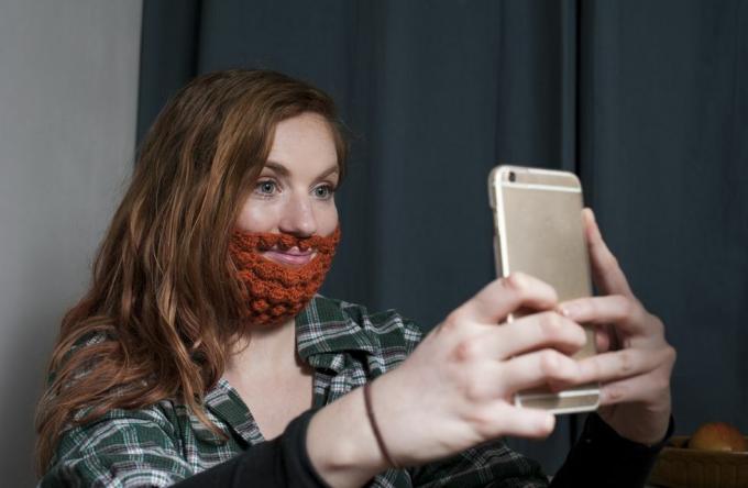 nainen, jolla on punainen virkattu parta, ottaa selfietä pyhän patrickin päivänä