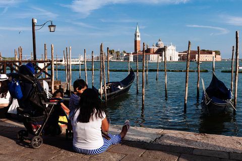 Turistit istuvat Venetsian kentällä katsellen San Giorgio -kirkkoa