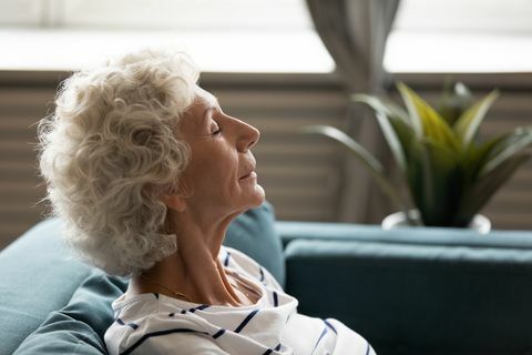 sivukuva lähikuva 60-luvun kasvot kypsä rauhallinen nainen silmät kiinni nauttia raikkaasta ilmasta viettää aikaa kotona nojaten sohvalle lepäämään hankkimassa henkistä ja fyysistä voimaa mindfulness meditaatio senioreille -konsepti