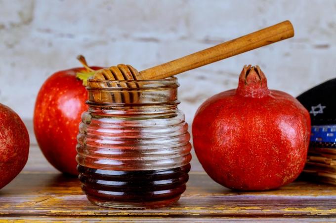 kaatamalla hunajaa omenalle ja granaattiomenalle hunajalla, juutalaisen uudenvuoden rosh hashanah -symboleilla