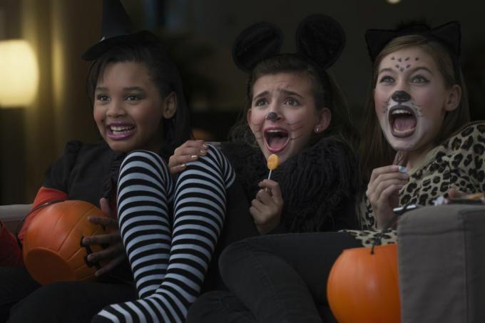 tytöt puvuissa katsomassa pelottavaa elokuvaa yhdessä halloweenina