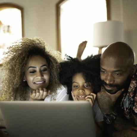 onnellinen perhe katsomassa elokuvaa kannettavalla tietokoneella
