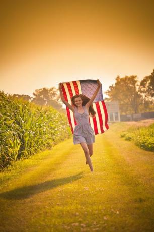 teini maatila tyttö kulkee kentän heiluttaen meille lippu