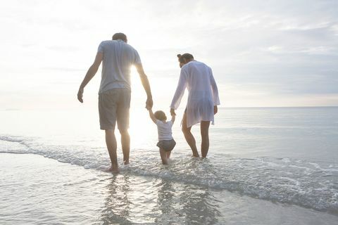 perhe kädessä kävellen rannalla