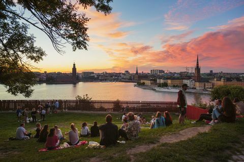 Ihmiset piknikillä puistossa panoraamanäkymällä Tukholman auringonlaskun aikaan, Ruotsi