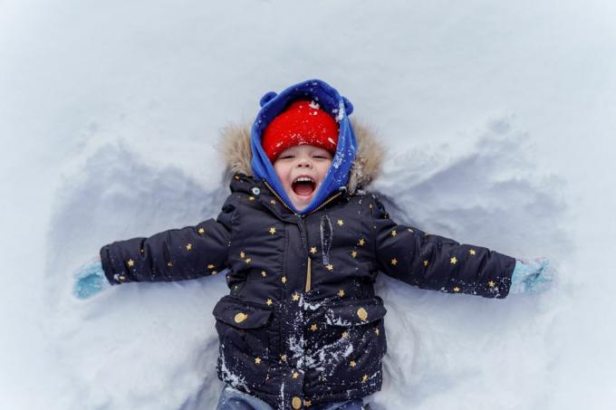 nuori lapsi lumessa tekemässä lumienkeliä