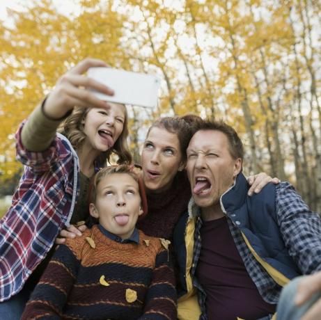 Tyhmä perhe ottaa selfietä ja tekee kasvoja syksyn puistossa