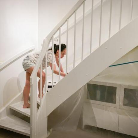 nainen soveltaa tuoretta valkoista maalia portaisiin